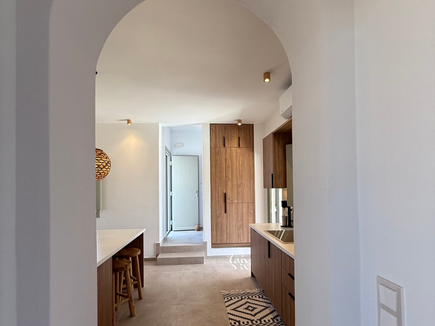 A soft plaster archway at DEON framing the kitchen and the entrance beyond
